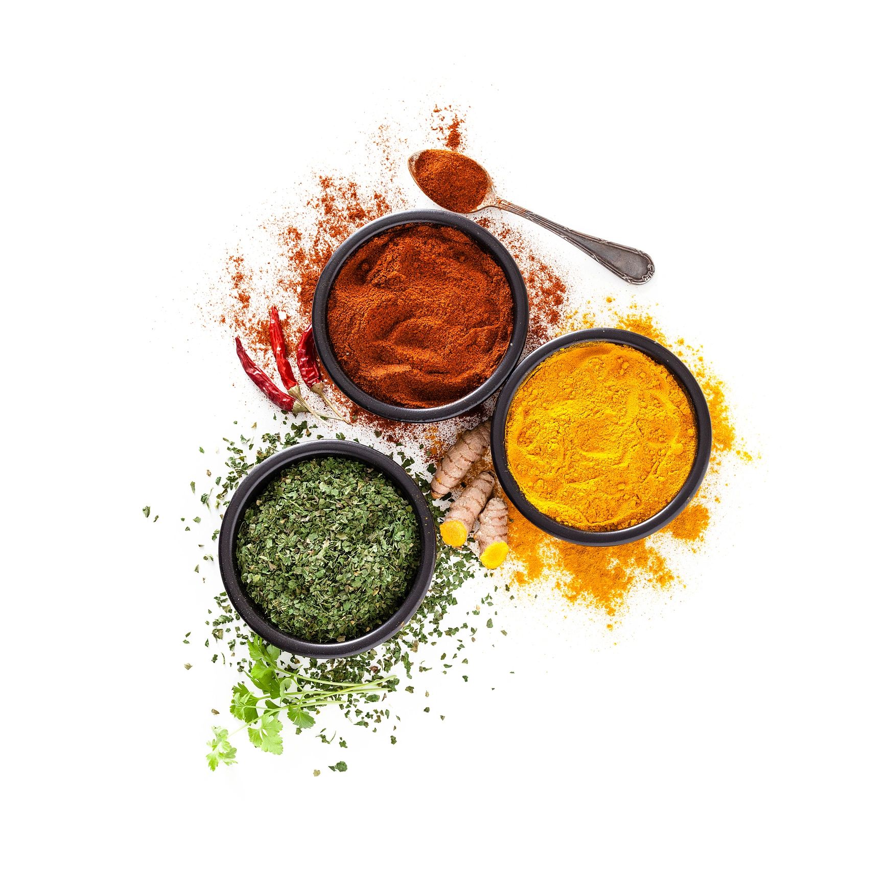 Turmeric, pepper powder, and dried parsley in bowls