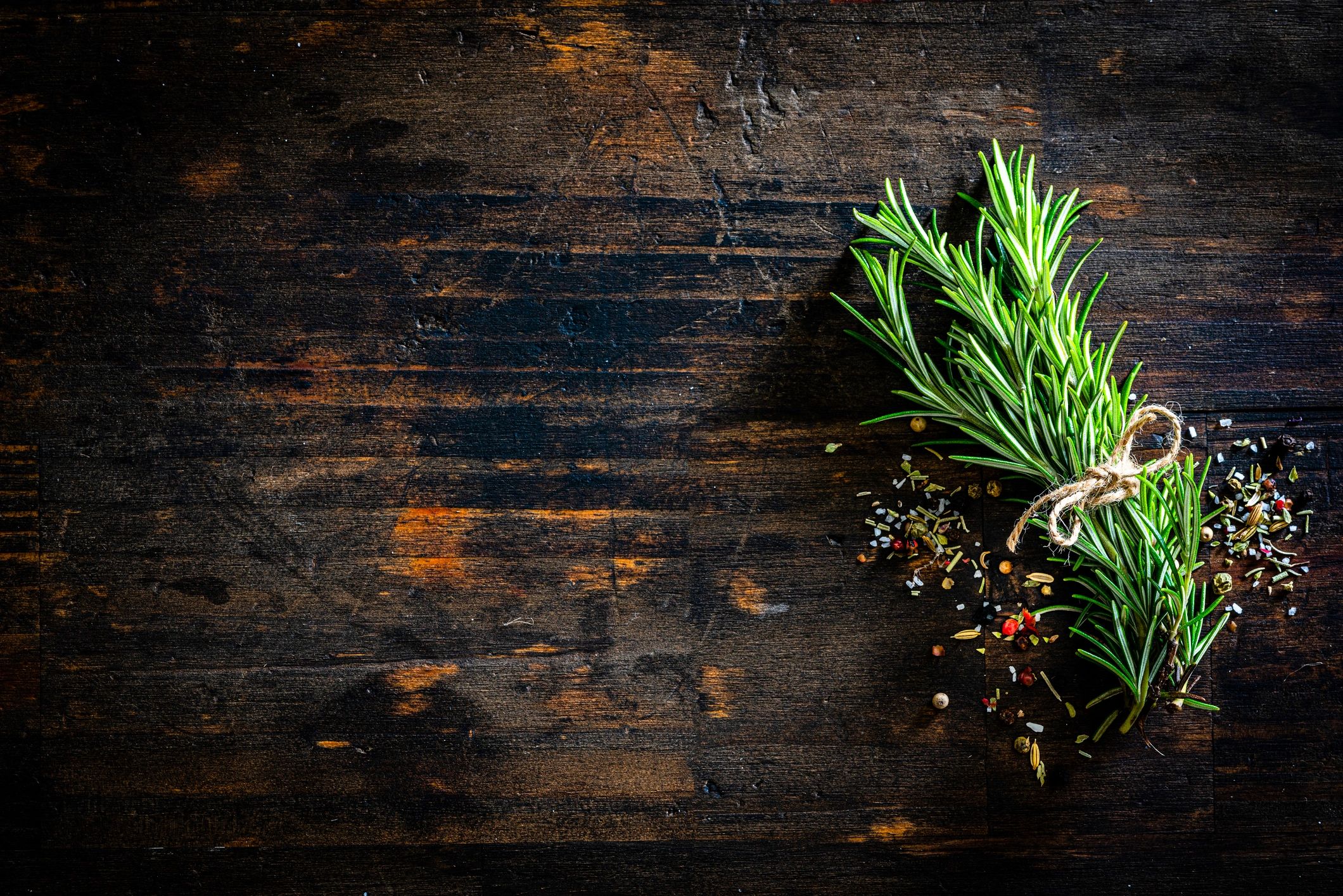 Close-up of rosemary, salt, and pepper on a rustic surface