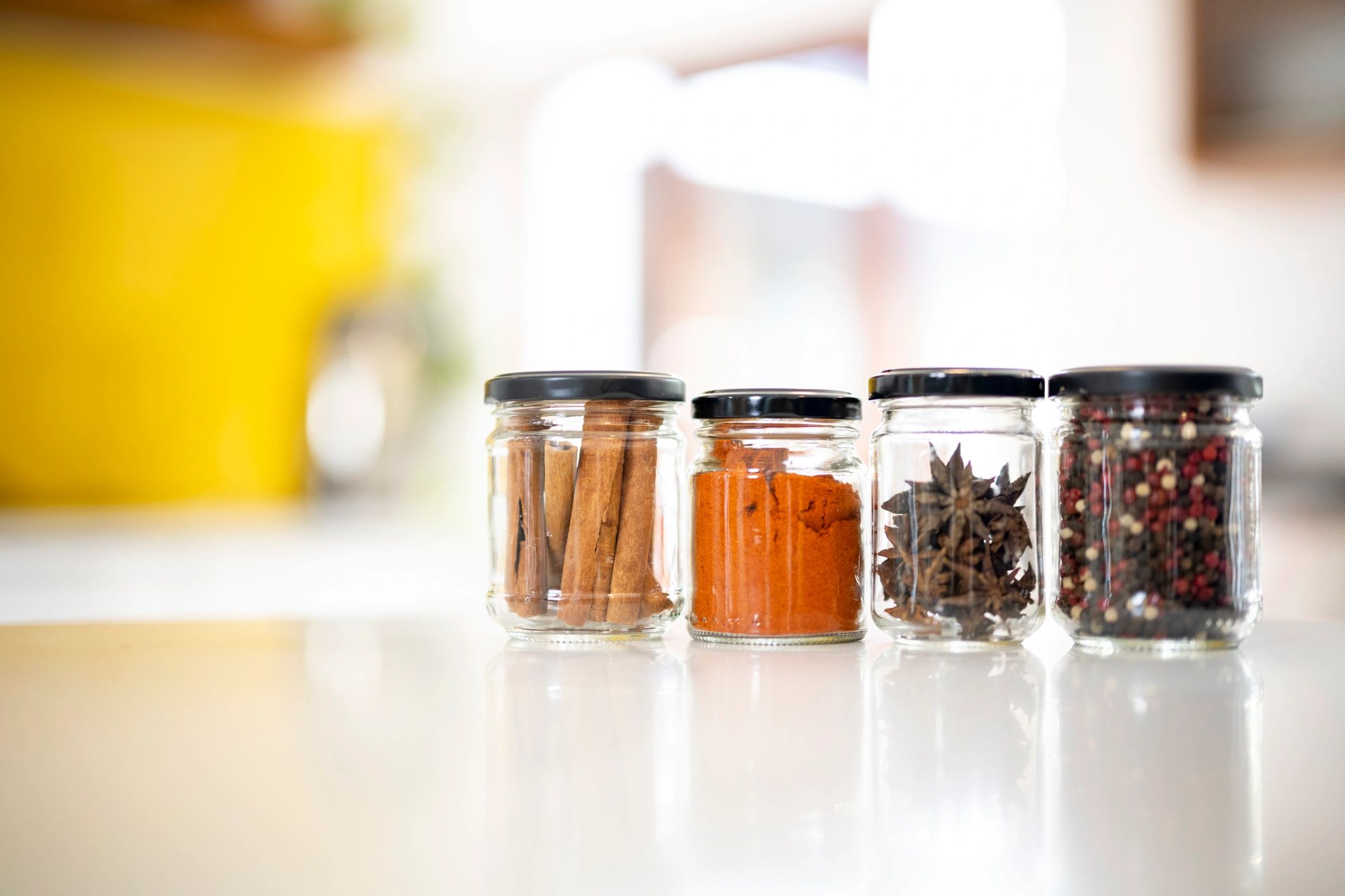 Glass jars filled with gourmet herbs and spices on a kitchen counter